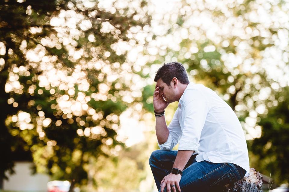 Man sitting down with hand on face struggling with Anxiety
